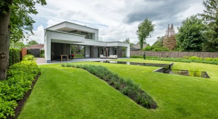 Achtertuin modern wit huis met zwemvijver en groot terras. 
