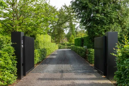 Inrit met poort aan moderne villa in groene omgeving