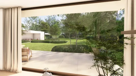 Zicht vanuit de woonkamer op het strakke terras en de aangrenzende tuin in Rijmenam.