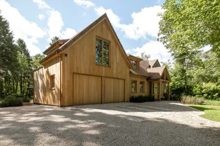 Houten villa met dubbele schuurpoort en grindoprit omringd door dennenbomen in Bonheiden