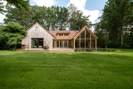 Achtergevel van de houten villa met glazen puntgevel en zwemvijver in Bonheiden
