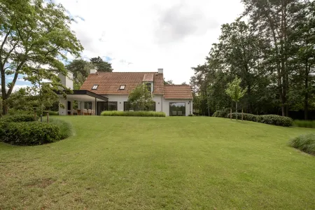 Golvend gazon met zicht op de witgekaleide villa en het overdekte terras