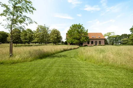 Gemaaid graspad dat uitloopt op de hoeve met haar karakteristieke oranje pannendak.