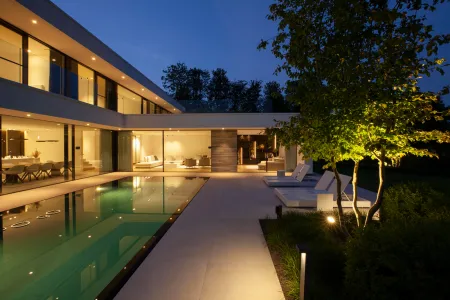 Een foto in het donker van een witte villa met zwembad.