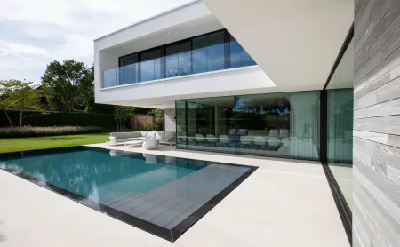 Een zwembad met terras tot aangrenst tegen een witte villa.