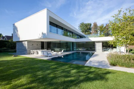 Witte villa met zwembad en groene tuin.