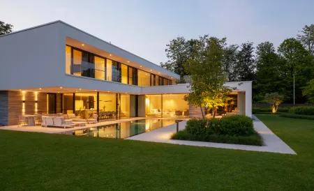 Een avondbeeld van een witte villa met zwembad.